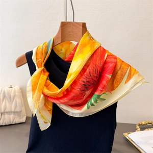 Detail showing high-quality floral print silk scarf styled with a navy blue vest and bag