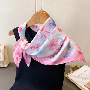 Close-up of floral silk scarf styled on a black vest highlighting soft texture and print