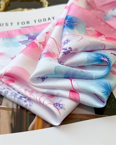 Detailed macro view of soft silk square scarf featuring watercolor floral patterns and satin gloss