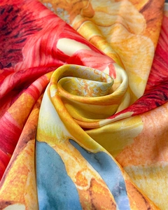 Detailed close-up of vibrant floral print silk scarf with elegant spiral draped texture