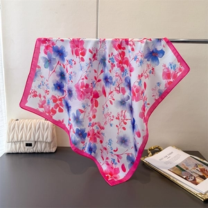 Detail of floral silk scarf with pink and blue prints hanging on a metal rod