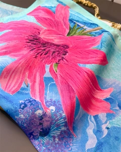 Detailed view of pink floral print on silk-like scarf with vibrant gradient background