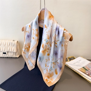 Floral print silk square scarf in purple and orange on an elegant wooden hanger