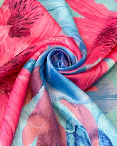 Close-up of vibrant pink floral print on blue silk-like square scarf with soft texture