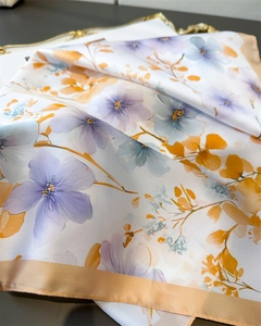 Close-up of silk-textured floral scarf with purple petals and champagne gold edges