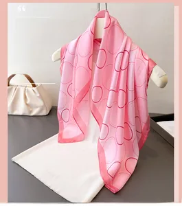 Detailed texture of pink silk scarf with geometric circle print hanging on white hanger