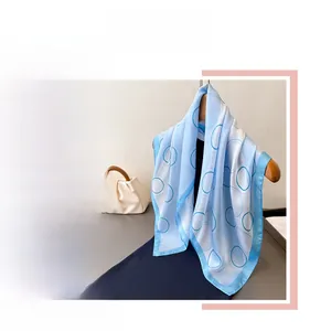 Detail view of light blue silk scarf with geometric circle patterns and dark navy border