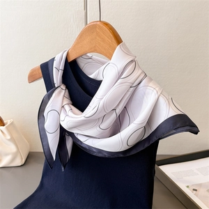 Detailed shot of silk-like scarf with geometric rings draped on a hanger with a blue vest