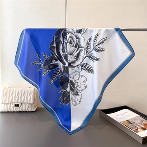 Detail of elegant floral silk scarf with blue border and monochrome rose prints