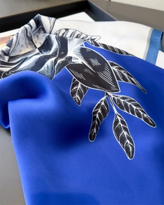 Detail of silk scarf with elegant navy blue and white floral leaf pattern and satin finish