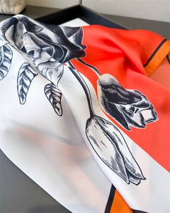 Detail of silk scarf showing dynamic folds and sketch-style rose print on vibrant orange