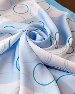 Macro shot of sky blue and white silk scarf with abstract circular patterns and satin gloss