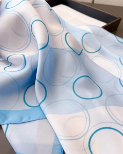 Detailed close-up of blue geometric circle silk scarf with fine rolled edges and smooth texture