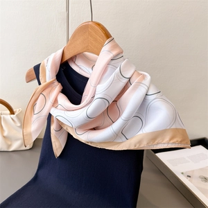 Elegant silk-like square scarf with pink and brown geometric patterns on navy top