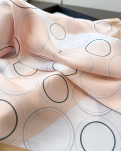 Detail of silk scarf showing soft peach and ivory folds with gray oval geometric patterns