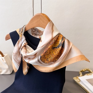 Detail of silk scarf with vintage peacock pattern tied on a knit vest over wood hanger