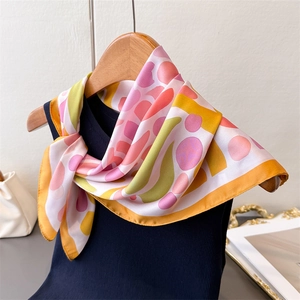 Détail d'un foulard en soie imprimé corail avec motifs abstraits sur un col de chemise