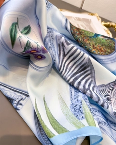 Detailed view of luxury silk scarf with zebra pattern, peacock feathers and rolled edge