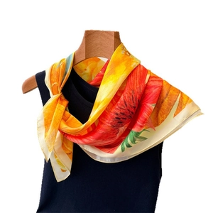 Floral silk square scarf with vibrant orange petals draped over a black vest on a wooden hanger