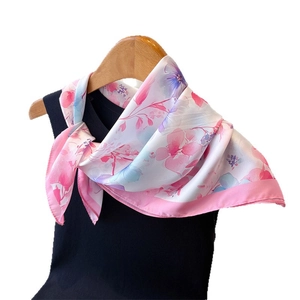 Floral print silk square scarf in pink and white elegantly draped on a hanger