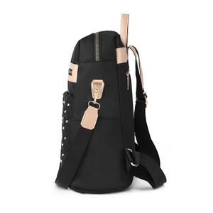 Black nylon backpack with gold studs and diamond quilting, side view on white background