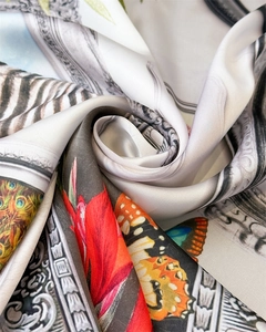Detailed view of silk-like scarf with vintage floral, peacock feathers, and butterfly patterns