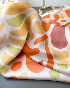 Détail d'un foulard en soie à imprimé corail montrant la texture satinée et les motifs