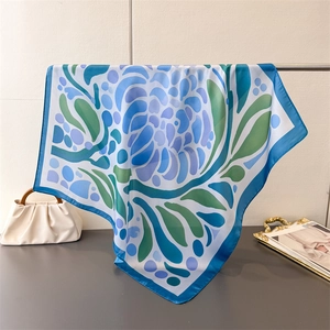 Gros plan d'un carré de soie aux imprimés floraux avec une finition de couture bleue raffinée