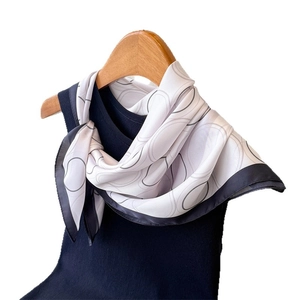 Elegant silk scarf with grey oval patterns and navy borders on a wooden hanger