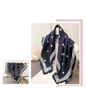 Détail d'un foulard en soie avec pois et bordures décoratives au drapé fluide