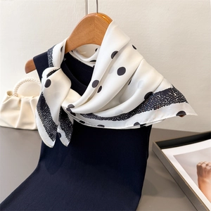 Élégant foulard en soie blanche à pois noirs drapé sur un cintre en bois chic