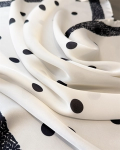 Gros plan détaillé d'un foulard en soie à pois montrant des drapés doux et un fini brillant