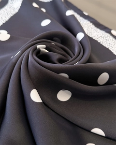 Gros plan montrant la texture soyeuse et les pois blancs sur l'élégant foulard en soie noire