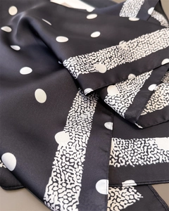 Détail d'un carré de soie aux motifs à pois blancs classiques et imprimé animalier élégant