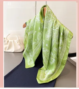 Detail of light green silk scarf with white floral patterns on a wooden hanger