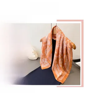 Detail of an orange silk scarf with elegant white paisley floral patterns on a hanger