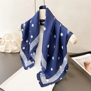 Foulard en soie bleu marine à pois sur un gilet blanc pour un look élégant