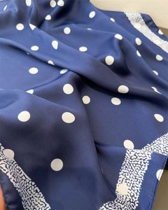 Détail macro d'un foulard en soie bleu marine avec pois blancs et texture lisse