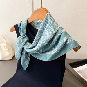 Detail of teal floral silk scarf with elegant scroll patterns draped on a black top