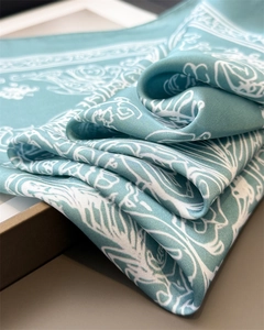 Close-up of light blue silk square scarf featuring elegant white floral prints and satin texture