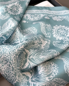 Detailed macro view of the aqua silk scarf showing soft folds and paisley patterns