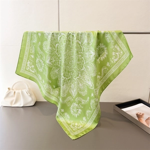 Detail of green silk-like square scarf featuring white mandala floral pattern and elegant sheen