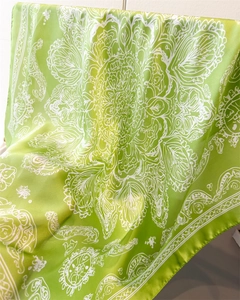 Detail of green silk-like scarf with white paisley patterns and smooth texture