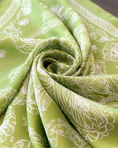 Close-up of green silk square scarf with white paisley patterns and soft glossy texture