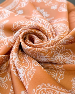Macro shot of orange paisley silk scarf fabric showing smooth satin texture and drape