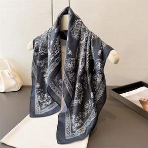 Elegant black and white floral printed silk scarf with satin luster on a white hanger