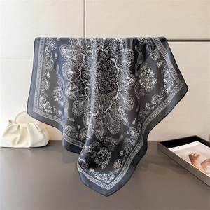 Detail of a black silk scarf with white paisley and elephant patterns on a metal rack