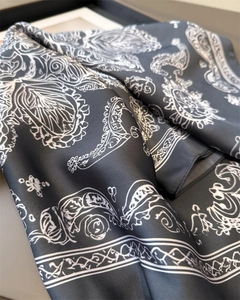 Close-up of black and white paisley print silk scarf with smooth glossy texture