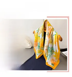 Detail of floral silk scarf with yellow and orange patterns on a white background