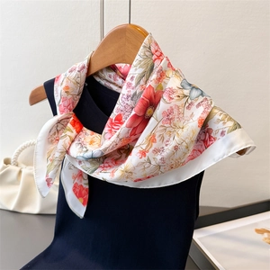 Detail of floral silk scarf with vibrant rose prints on a white base fabric